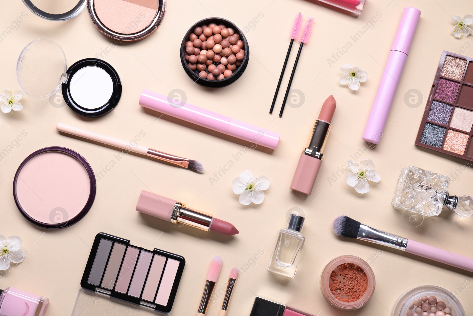 Photo of Flat lay composition with different makeup products and beautiful spring flowers on beige background