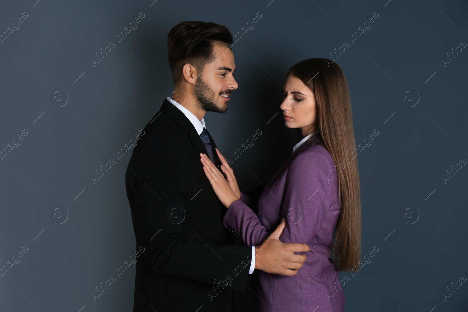 Photo of Boss molesting his female secretary on dark background. Sexual harassment at work