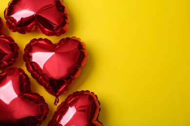 Photo of Red heart shaped balloons on yellow background, space for text. Valentine's Day celebration