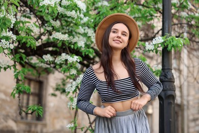 Photo of Beautiful woman in hat near blossoming tree on spring day