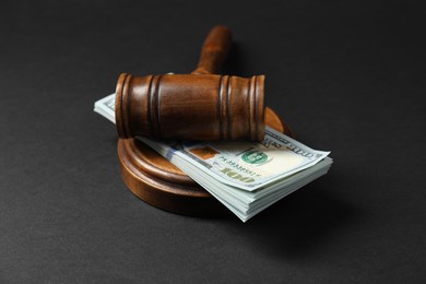 Photo of Law gavel with stack of dollars on black table