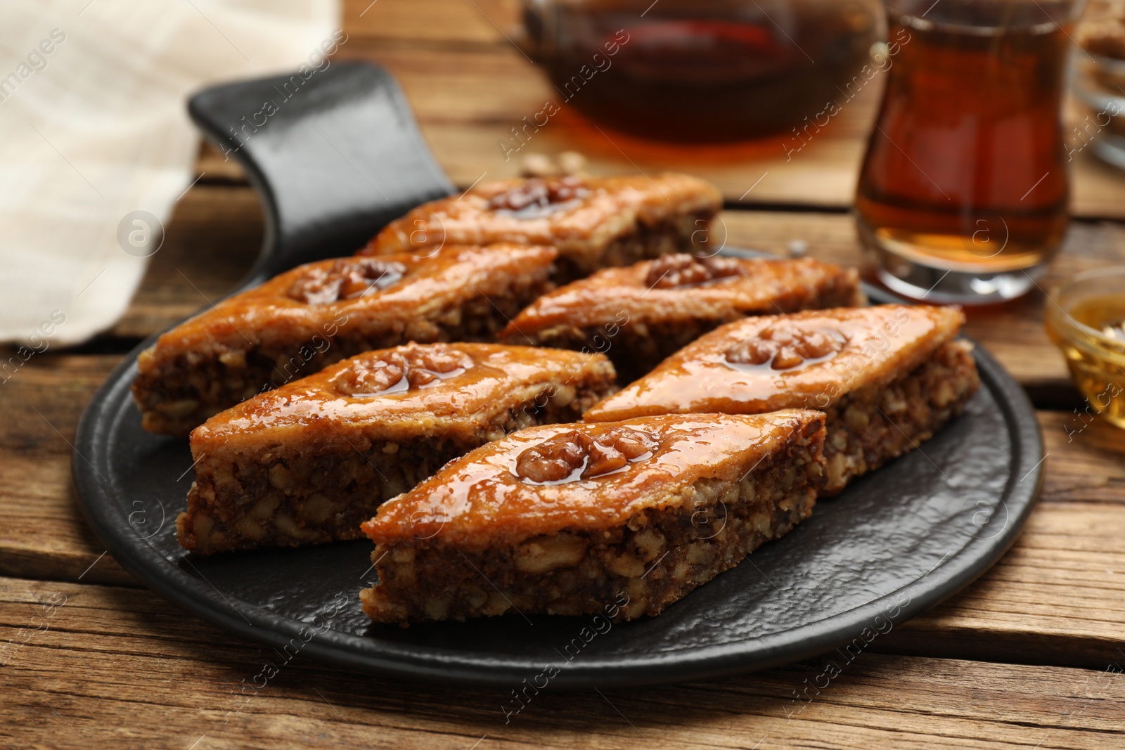 Photo of Delicious sweet baklava with walnuts on wooden table, closeup