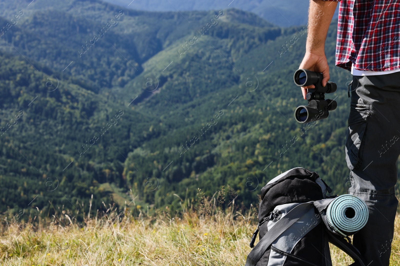 Photo of Back view of tourist with hiking equipment and binoculars in mountains, closeup