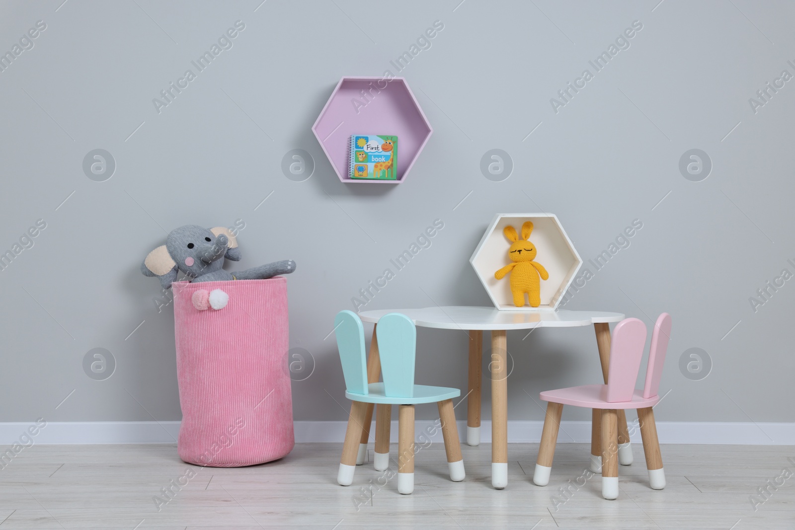 Photo of Kindergarten interior. Stylish furniture and toys near grey wall