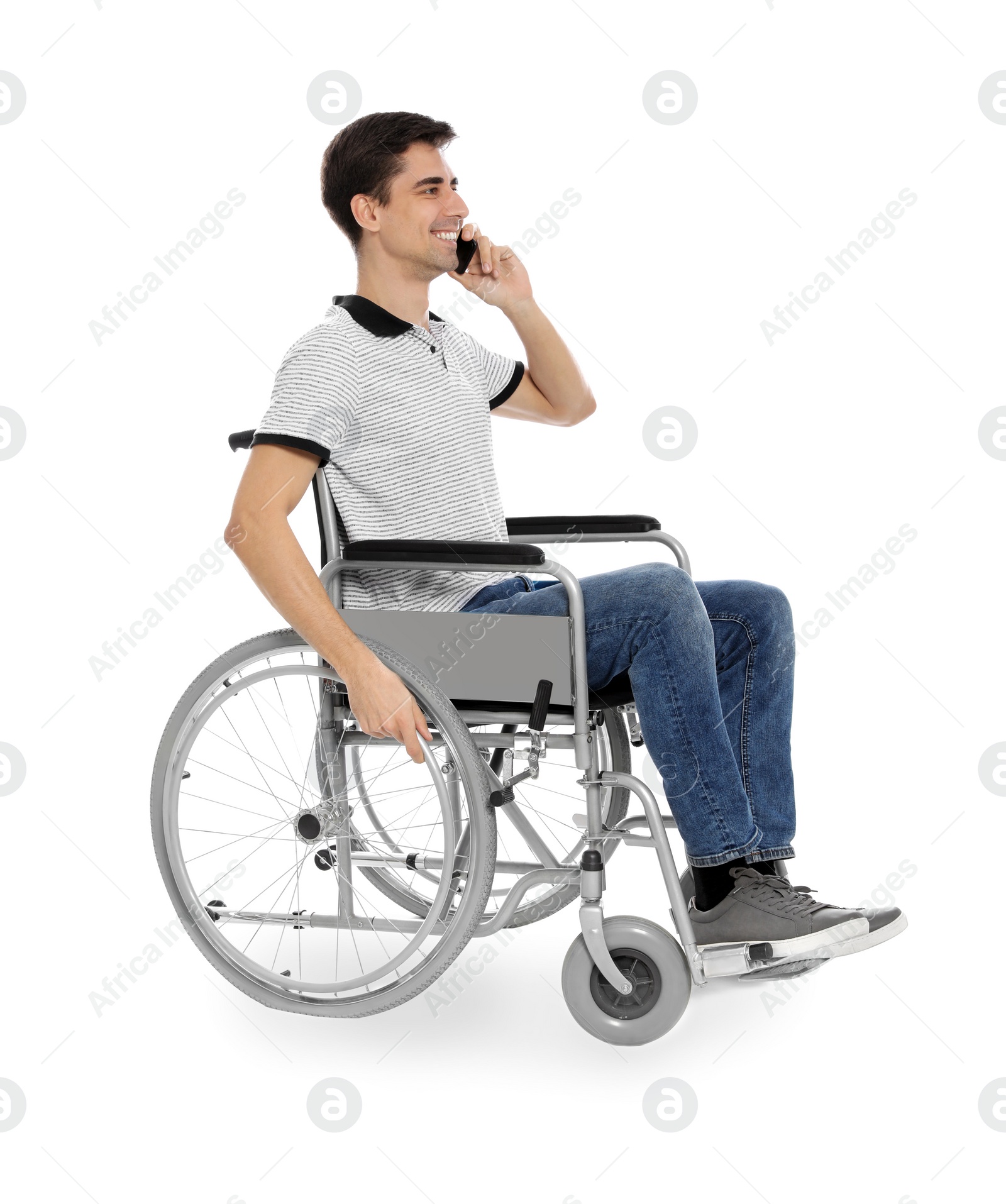 Photo of Young man in wheelchair talking by mobile phone isolated on white