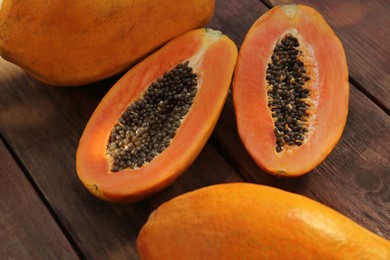 Photo of Fresh ripe cut and whole papaya fruits on wooden table, closeup