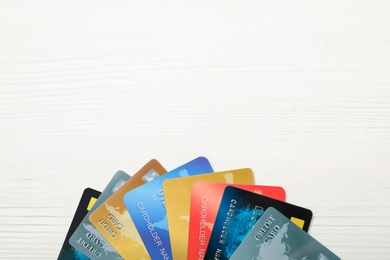 Photo of Many different credit cards on white wooden table, flat lay. Space for text