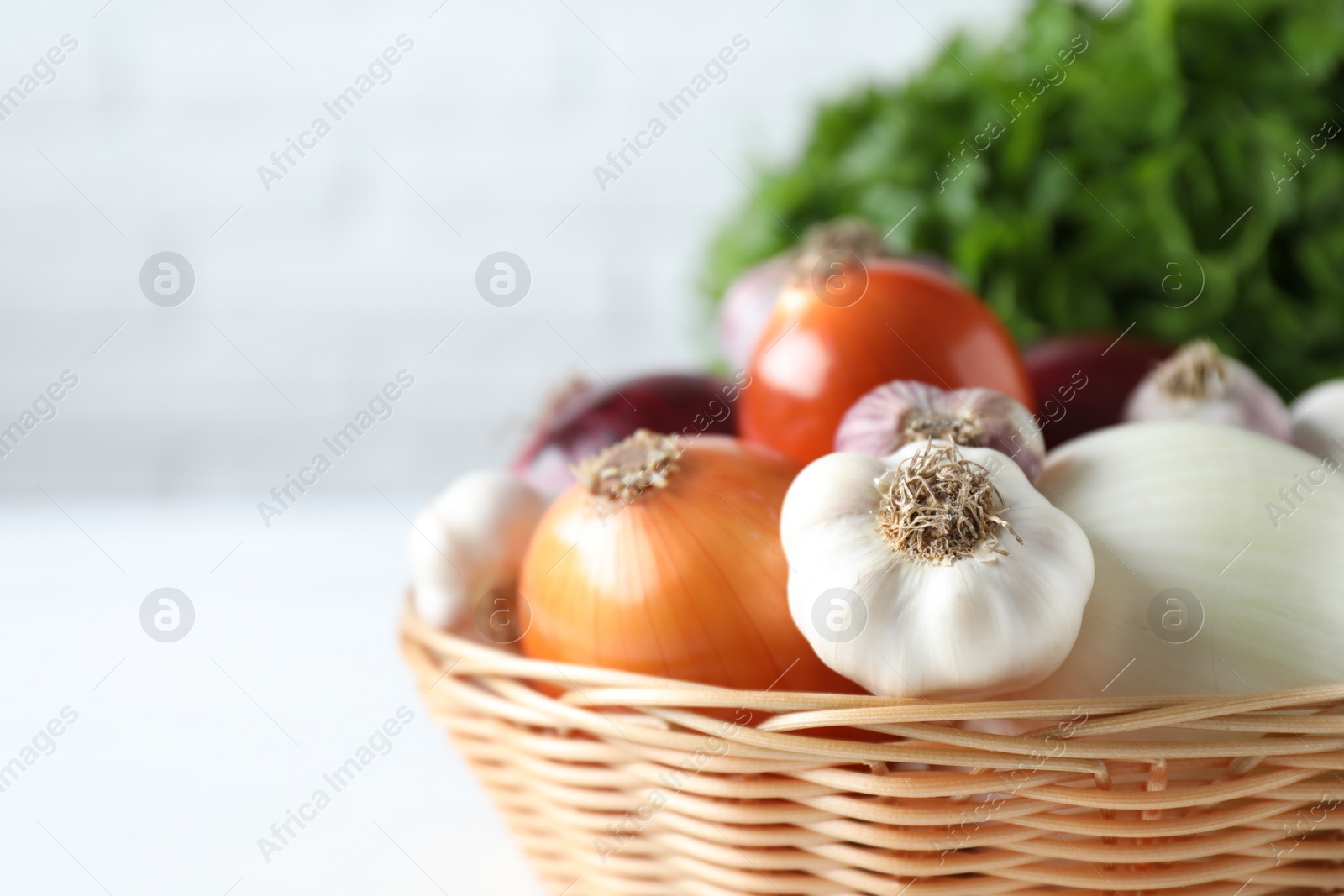 Photo of Fresh raw garlic and onions in wicker basket, closeup. Space for text