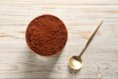 Photo of Delicious tiramisu in glass and spoon on light wooden table, top view