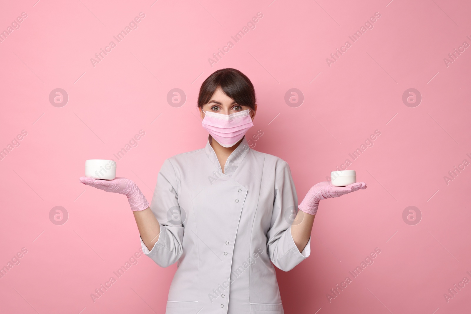 Photo of Cosmetologist with cosmetic products on pink background