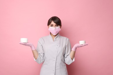 Photo of Cosmetologist with cosmetic products on pink background