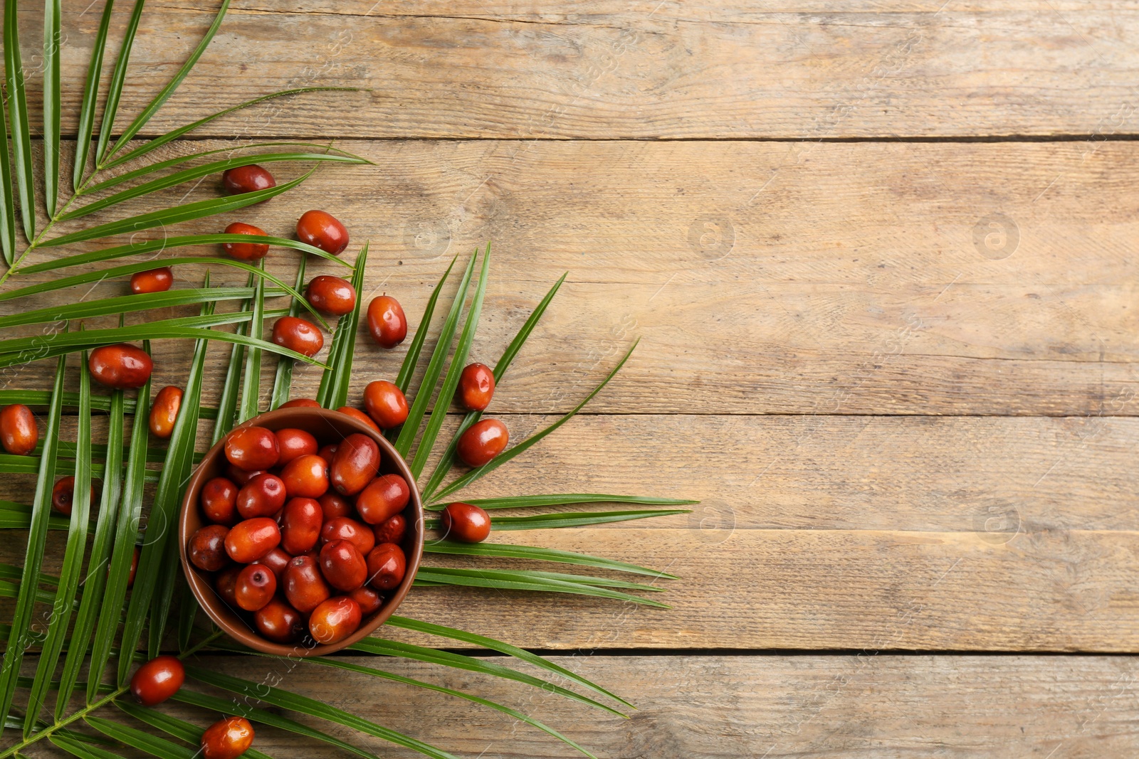 Photo of Palm oil fruits in bowl on wooden table, flat lay. Space for text