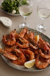 Photo of Plate of delicious cooked shrimps served with lemon and wine at table