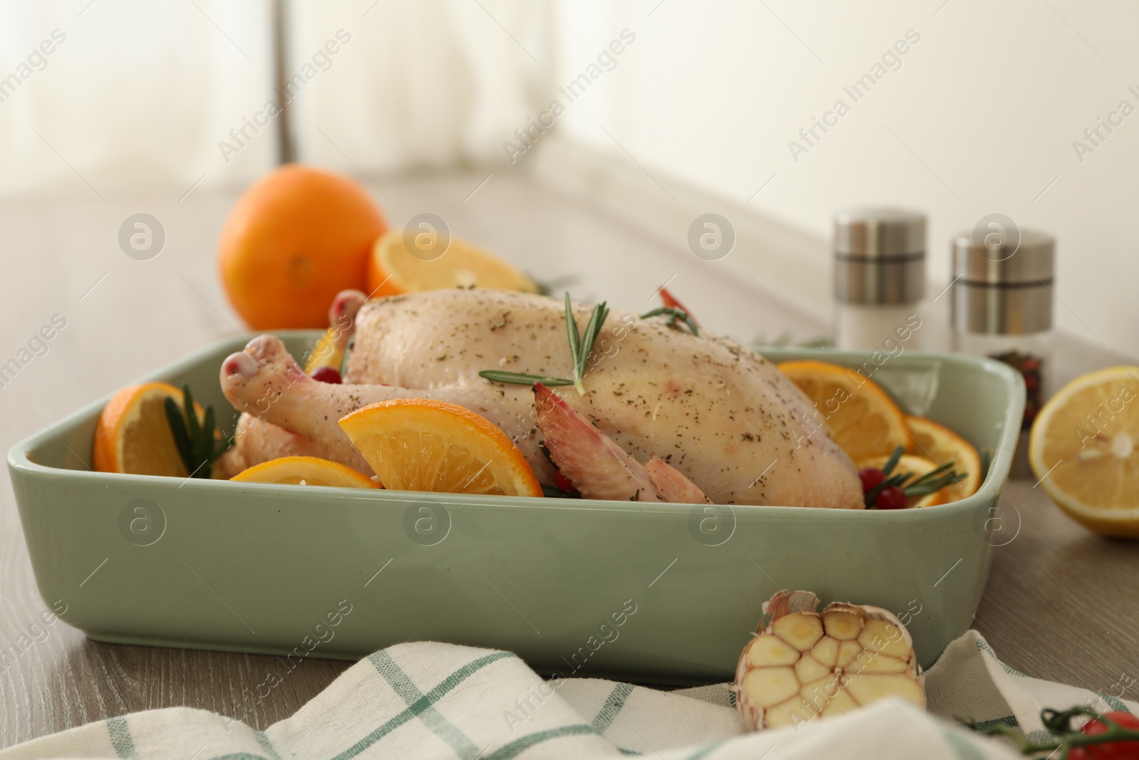 Photo of Chicken with orange slices in baking pan on wooden table