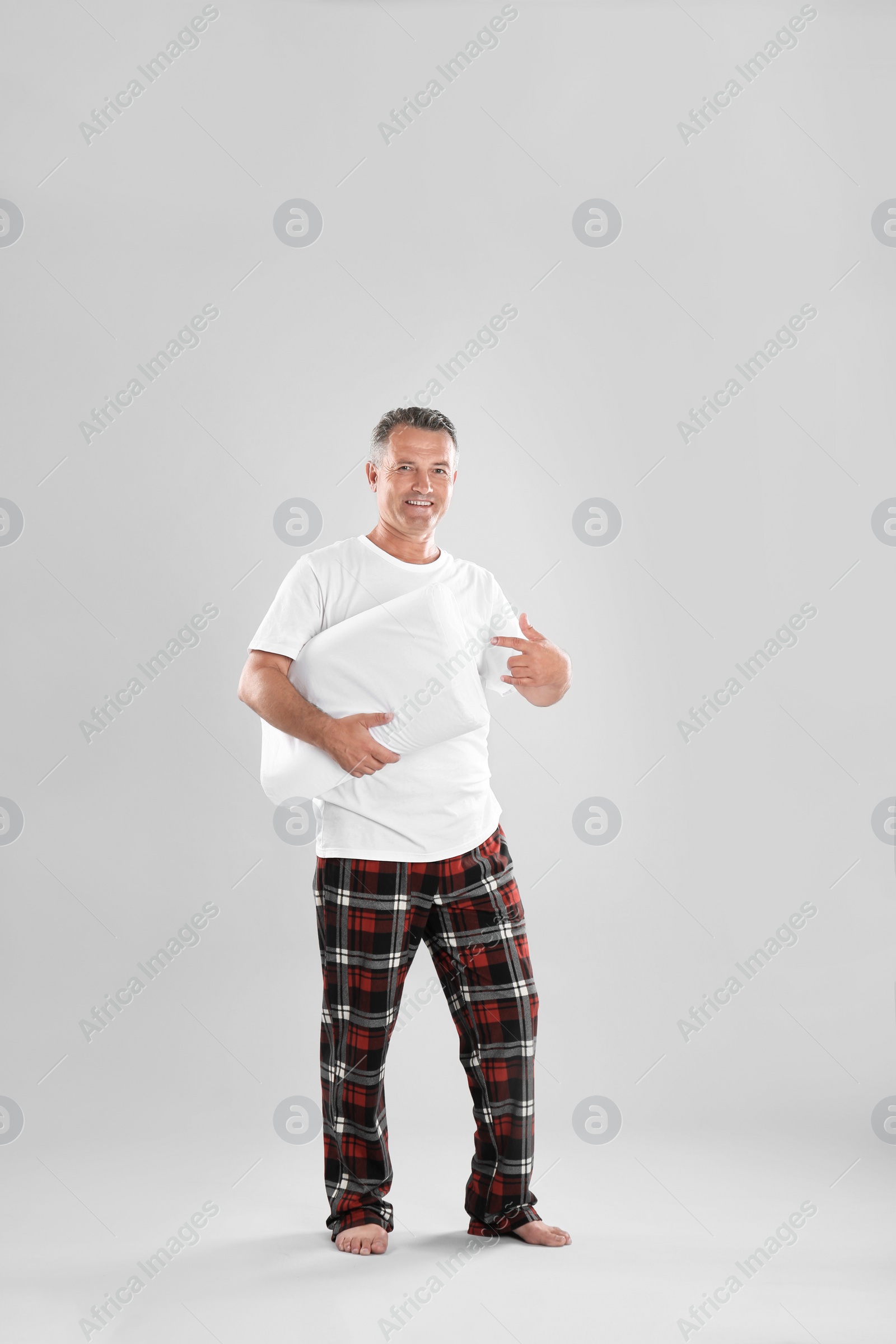 Photo of Man holding soft pillow on light background