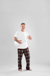 Photo of Man holding soft pillow on light background