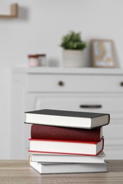 Photo of Stack of hardcover books on wooden table indoors