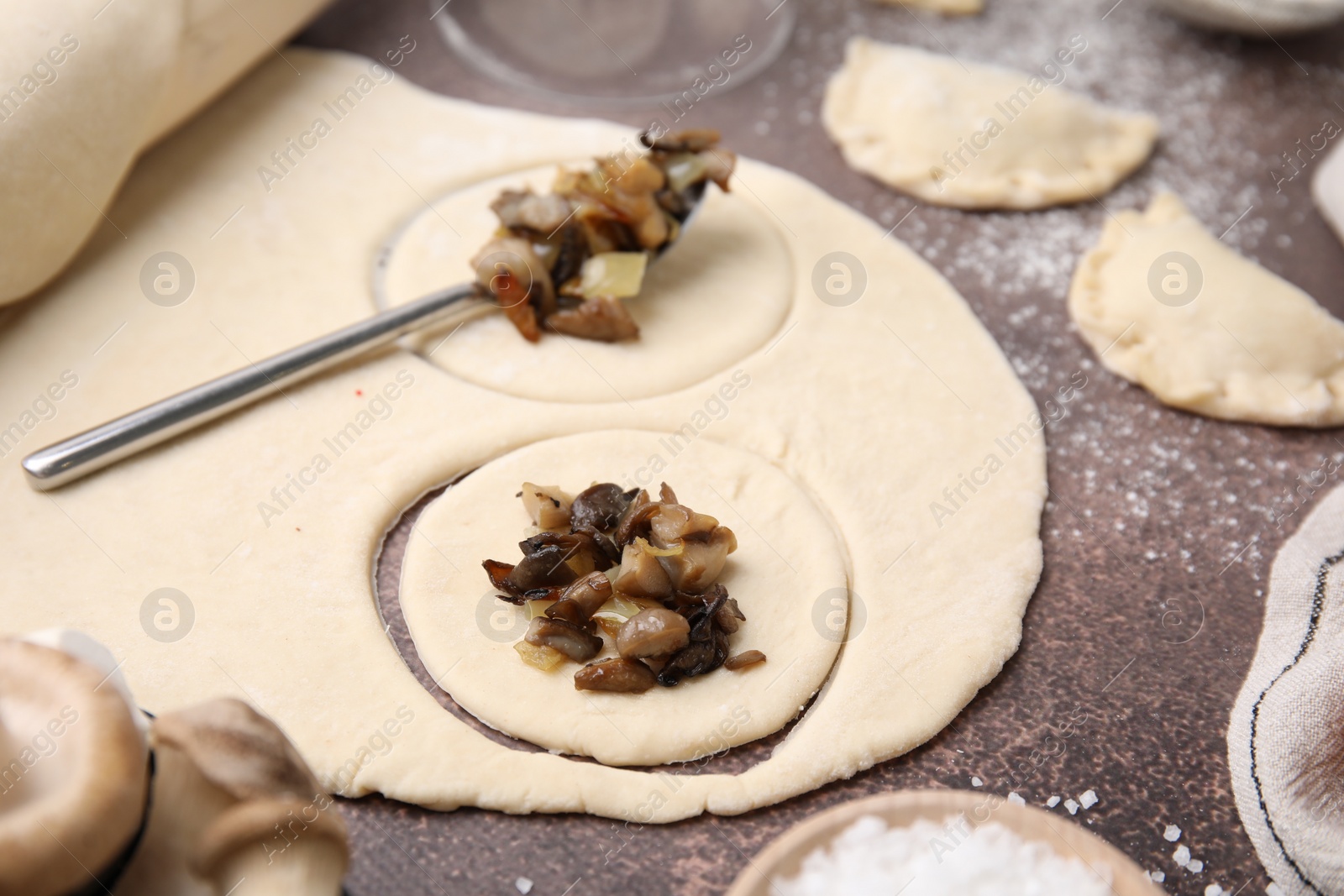 Photo of Process of making dumplings (varenyky) with mushrooms. Raw dough and ingredients on grey table, closeup