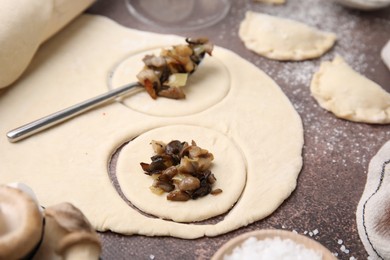 Process of making dumplings (varenyky) with mushrooms. Raw dough and ingredients on grey table, closeup