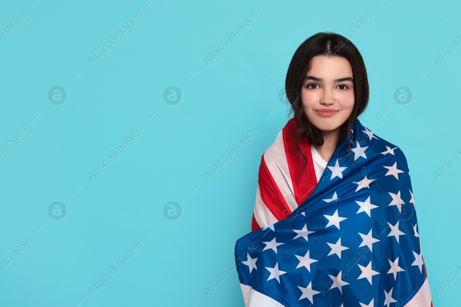 Photo of 4th of July - Independence Day of USA. Happy girl with American flag on light blue background, space for text