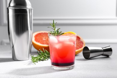 Photo of Delicious cocktail, grapefruit, rosemary and bartender equipment on light grey table