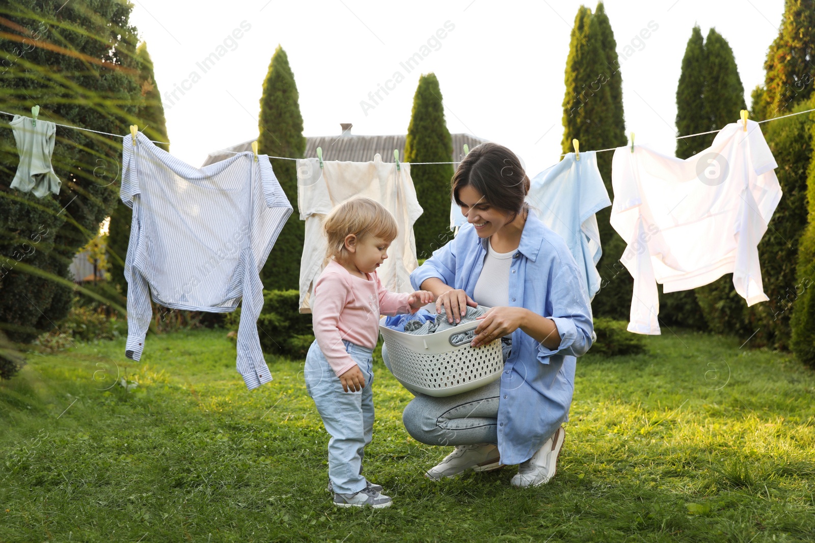 Photo of Mother and daughter near washing line with drying clothes in backyard