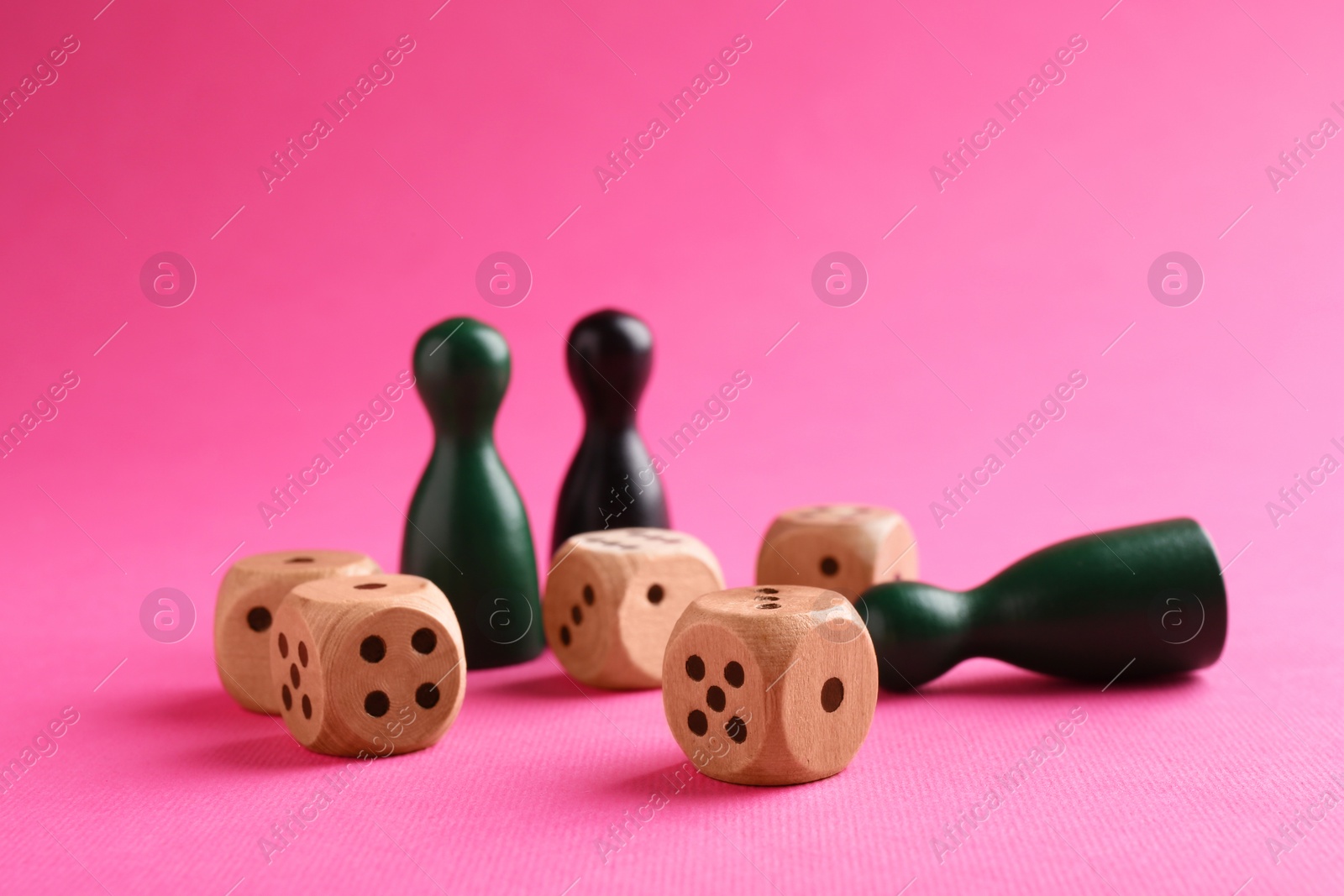 Photo of Wooden dices and color game pieces on pink background, closeup