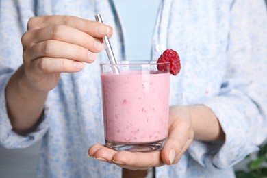 Woman holding glass of tasty raspberry smoothie, closeup