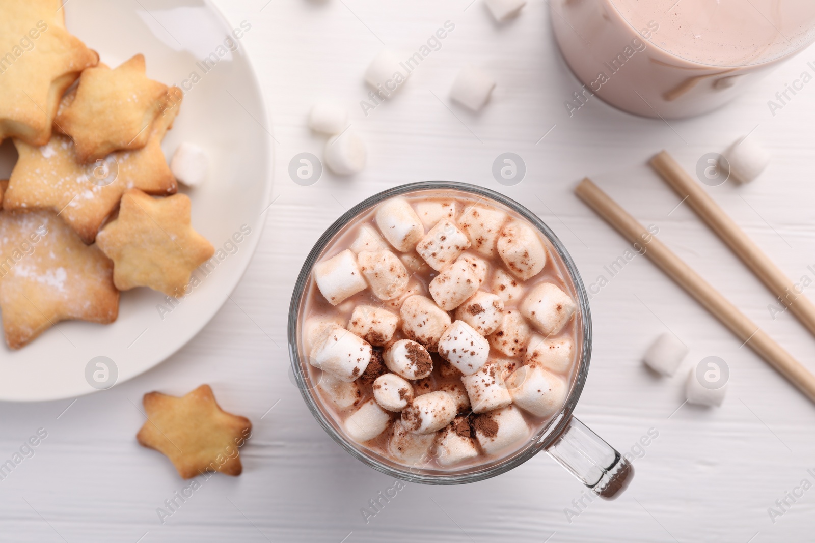 Photo of Cup of aromatic hot chocolate with marshmallows, cocoa powder and tasty cookies on white wooden table, flat lay