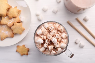 Cup of aromatic hot chocolate with marshmallows, cocoa powder and tasty cookies on white wooden table, flat lay