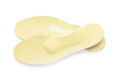 Pair of beige orthopedic insoles on white background, top view