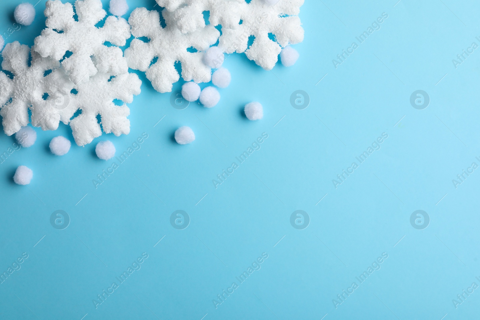 Photo of Beautiful snowflakes and decorative balls on light blue background, flat lay. Space for text