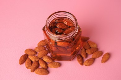 Photo of Jar with almonds and honey on pink background