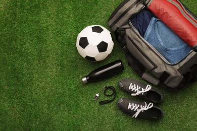 Photo of Gym bag and sports equipment on green grass, flat lay. Space for text