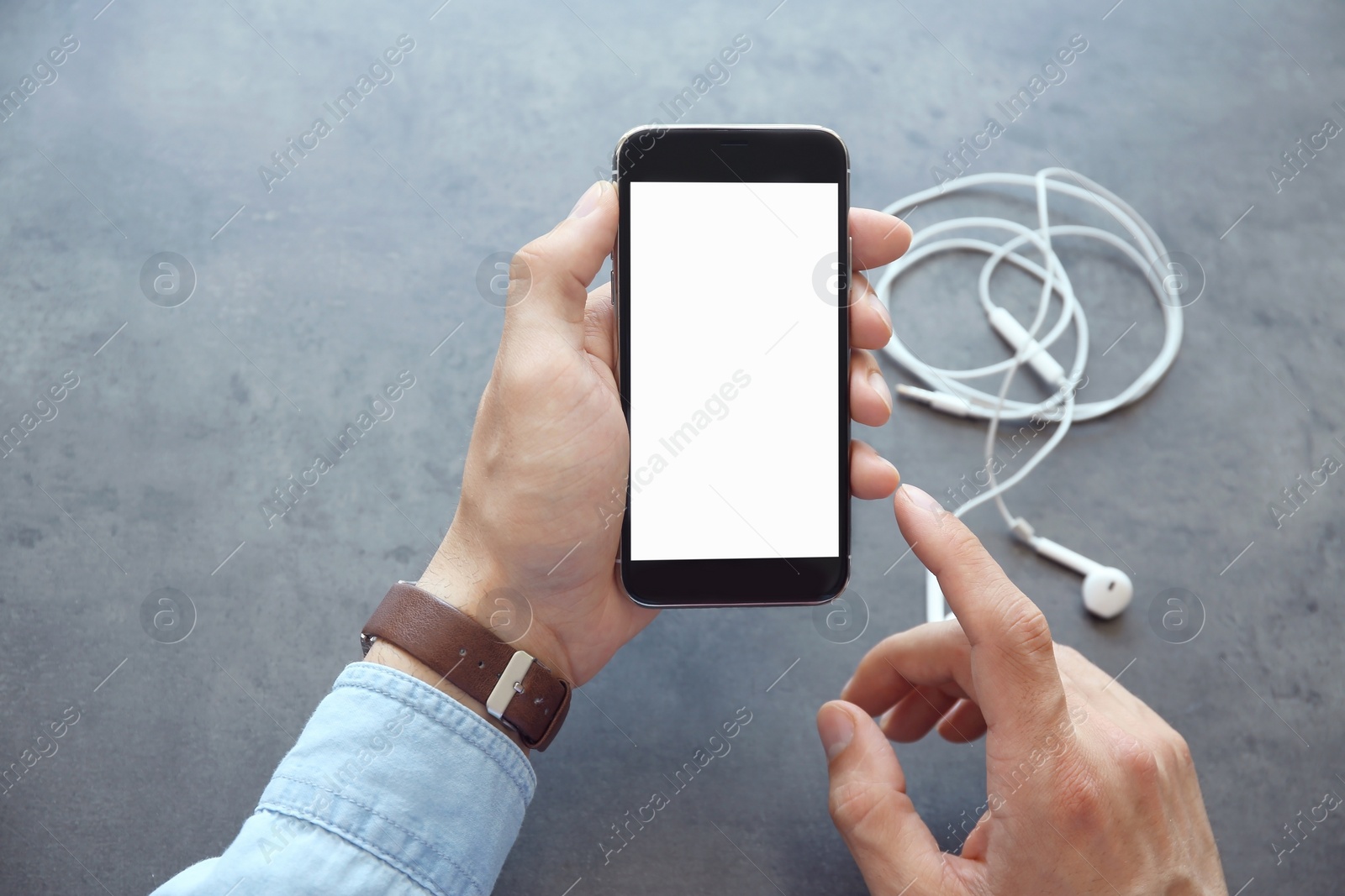 Photo of Young man holding mobile phone with blank screen in hand over table