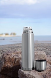 Metallic thermos and cap on stone near sea