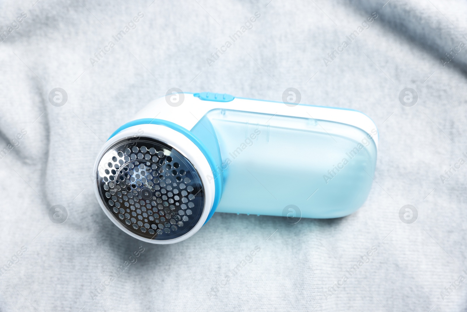 Photo of Modern fabric shaver on light grey cloth, closeup