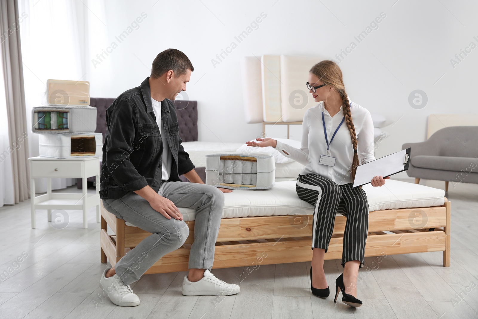 Photo of Young saleswoman consulting man in mattress store