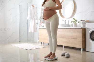 Photo of Pregnant woman standing on scales in bathroom, closeup