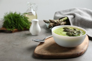 Photo of Delicious asparagus soup served on grey table