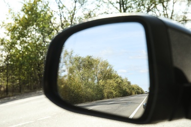 Photo of Closeup of car side rear view mirror on sunny day