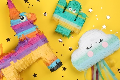 Photo of Different bright pinatas on yellow background, flat lay