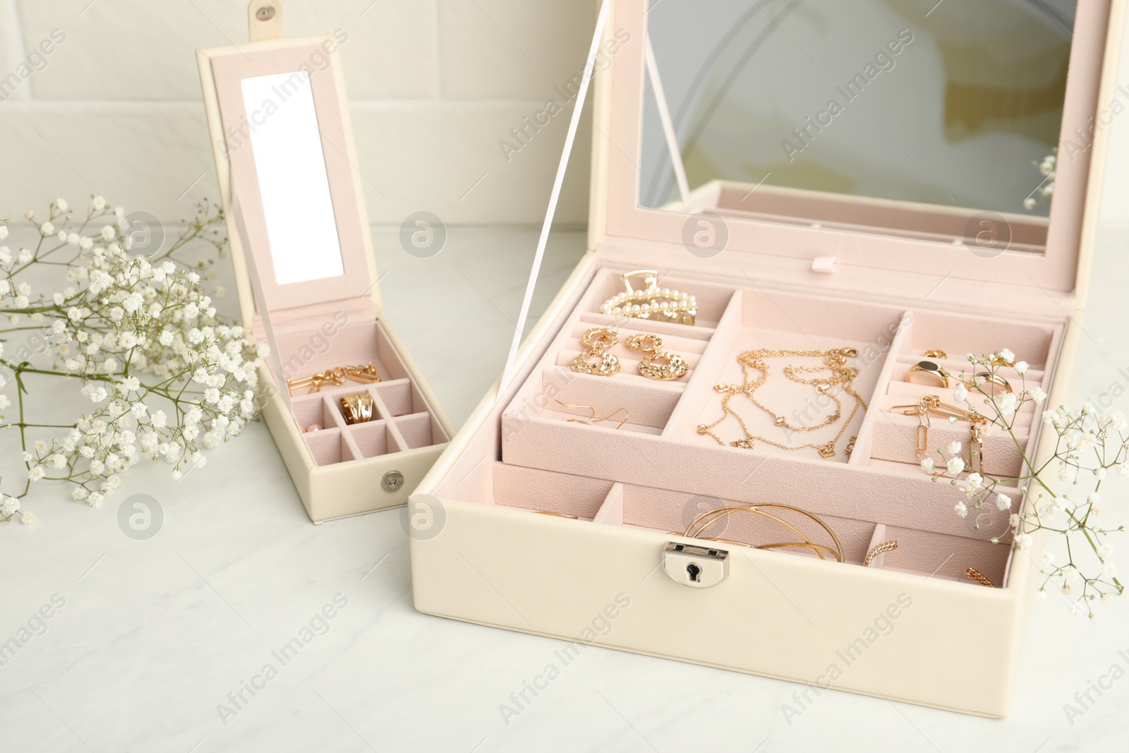 Photo of Jewelry boxes with different elegant bijouterie and flowers on white table