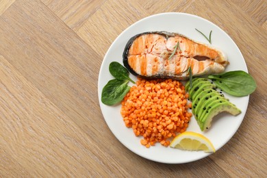 Photo of Plate with healthy food high in vegetable fats on wooden table, top view. Space for text