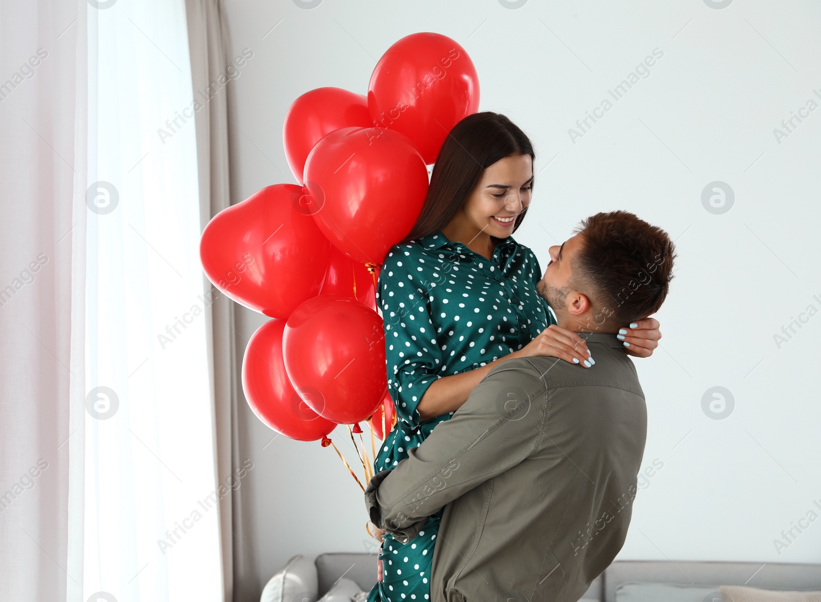 Photo of Young couple with air balloons at home. Celebration of Saint Valentine's Day