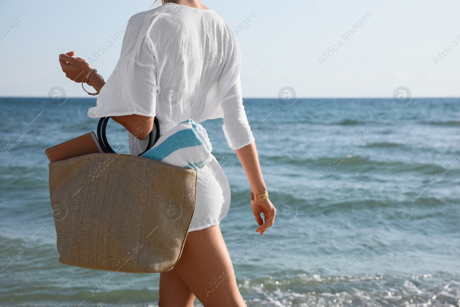 Photo of Woman carrying bag with beach towel near sea, closeup