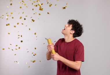 Photo of Emotional young man blowing up party popper on light grey background