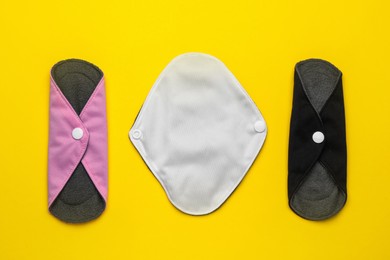 Photo of Reusable cloth menstrual pads on yellow background, flat lay