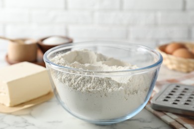 Photo of Making shortcrust pastry. Flour in bowl on white marble table