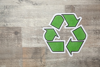 Photo of Paper recycling symbol on wooden background, top view. Space for text